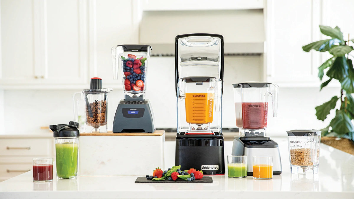 The Blendtec blender range on a bright white bench with fresh juices and berries